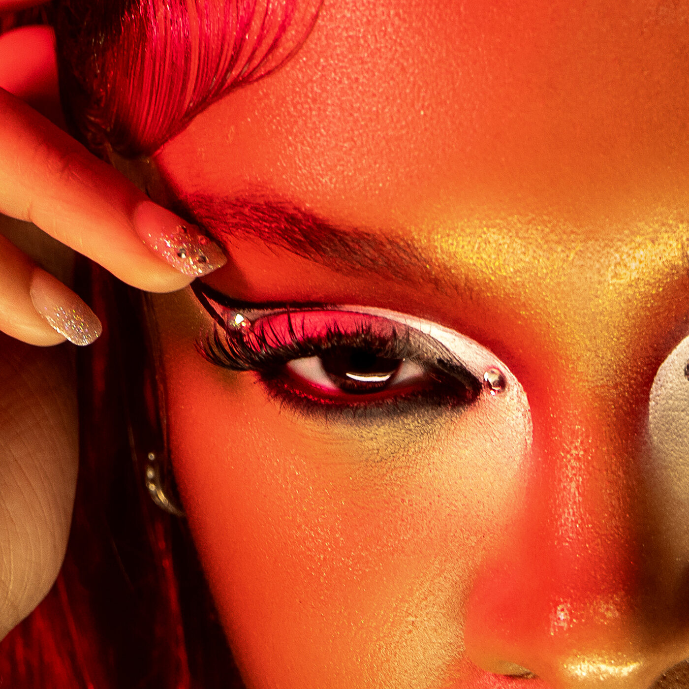 Featured editorial beauty portrait, close detail of eye makeup in red and gold tones